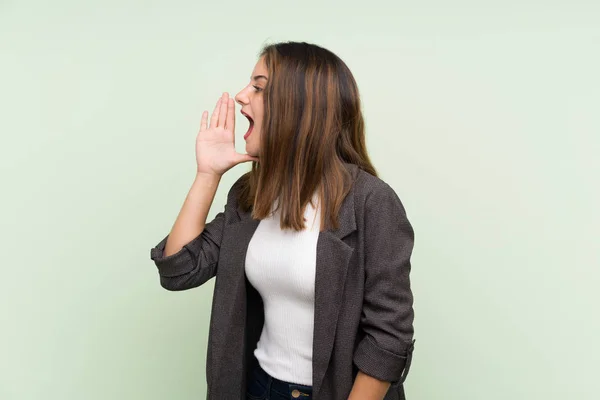 Junge Brünette Mädchen Mit Blazer Über Isoliertem Grünem Hintergrund Schreit — Stockfoto