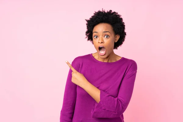 Африканська Американка Через Ізольоване Рожеве Тло Здивована Вказуючи Бік — стокове фото
