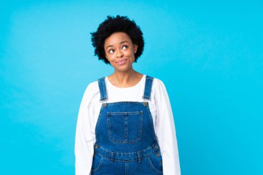 Afro-amerikan kadın, mavi bir arka planı var, gülüyor ve yukarı bakıyor.