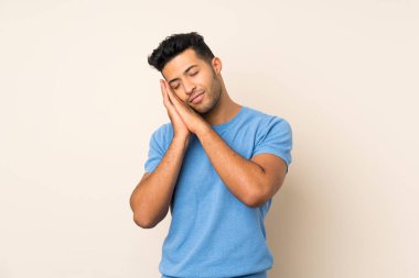 Soyutlanmış arka planda genç yakışıklı bir adam uyku jesti yapıyor.