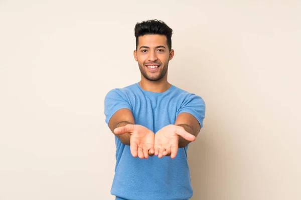 Joven Hombre Guapo Sobre Fondo Aislado Sosteniendo Espacio Copia Imaginario —  Fotos de Stock