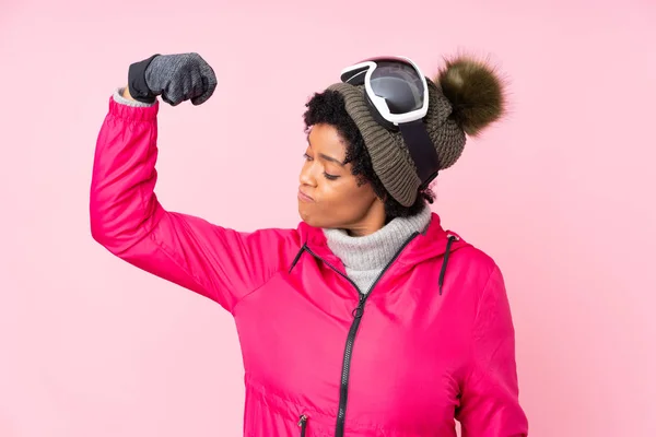 アフリカ系アメリカ人のスキーヤー女性でスノーボード眼鏡上の隔離されたピンクの背景は強いジェスチャーを作る — ストック写真