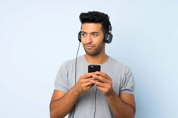 Joven Hombre Guapo Sobre Fondo Aislado Utilizando Móvil Con Auriculares —  Fotos de Stock