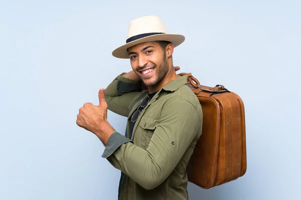 Joven hombre guapo sosteniendo un maletín vintage sobre fondo azul aislado — Foto de Stock