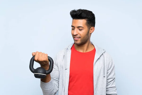 Sport uomo che fa sollevamento pesi con kettlebell oltre isolato muro blu — Foto Stock