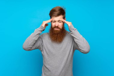 Kızıl saçlı, uzun sakallı, mavi arka planda, baş ağrısı olan bir adam.