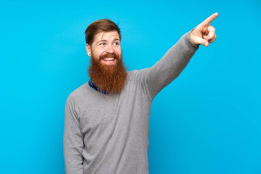 Uzun sakallı, soyutlanmış mavi arka planı olan kızıl saçlı bir adam.