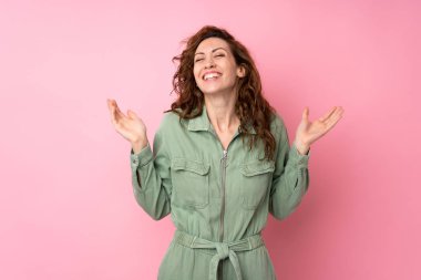 Soyutlanmış pembe arka planda genç ve güzel bir kadın. Gülümsüyor.