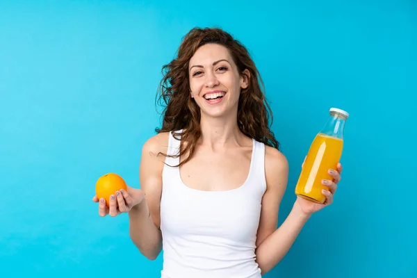 Ung Kvinna Med Lockigt Hår Håller Orange Över Isolerad Blå — Stockfoto