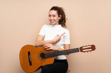 Arka planda gitar çalan genç bir kadın şaşırdı ve parmağıyla kenarı gösterdi.