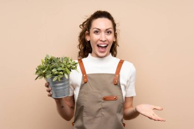 Bahçıvan kadın elinde şok olmuş bir yüz ifadesiyle bir bitki tutuyor.