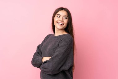 Kolları bağlı ve mutlu bir şekilde pembe arka planda yaşayan genç bir kadın.