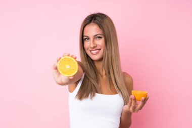 Sarışın bir kadın, izole edilmiş arka planda elinde bir portakal tutuyor.