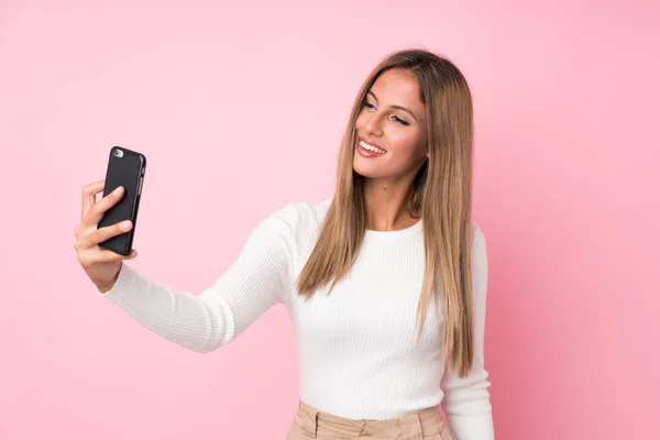 Młoda Blondynka Odizolowanym Różowym Tle Robi Sobie Selfie Komórką — Zdjęcie stockowe