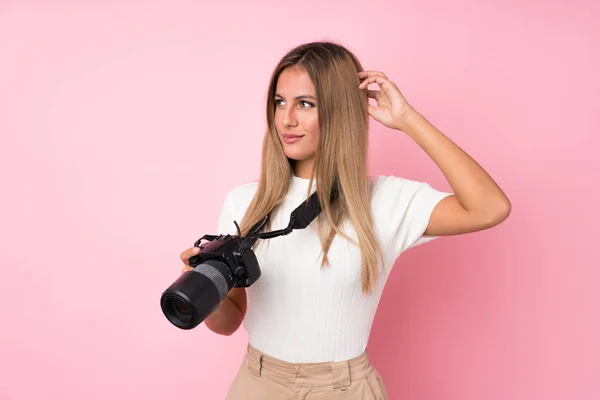 Mujer Rubia Joven Sobre Fondo Rosa Aislado Con Una Cámara —  Fotos de Stock