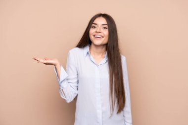 Arka planda izole edilmiş genç bir kadın, bir ilan vermek için avucunun içinde hayali bir alan tutuyor.