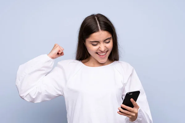 Ung Kvinna Över Isolerad Blå Bakgrund Med Hjälp Mobiltelefon — Stockfoto