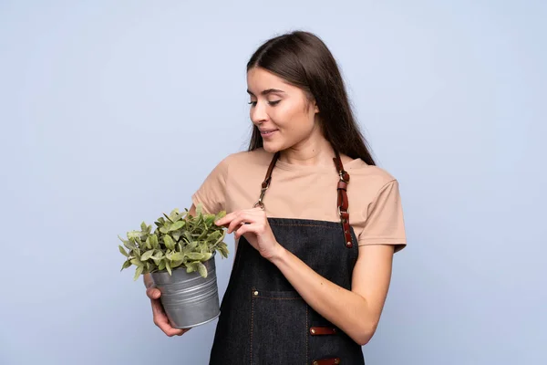 Jonge Vrouw Geïsoleerde Blauwe Achtergrond Het Nemen Van Een Bloempot — Stockfoto