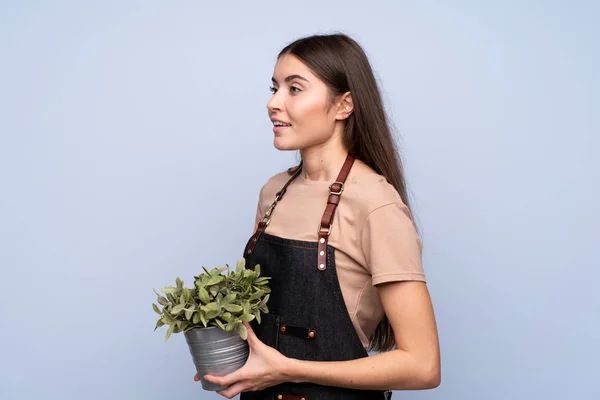 Jonge Vrouw Geïsoleerde Blauwe Achtergrond Het Nemen Van Een Bloempot — Stockfoto