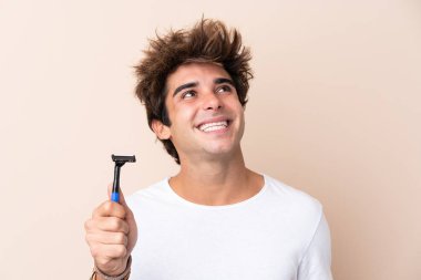 Sakalını kesen yakışıklı genç adam gülümserken kafasını kaldırıyor.