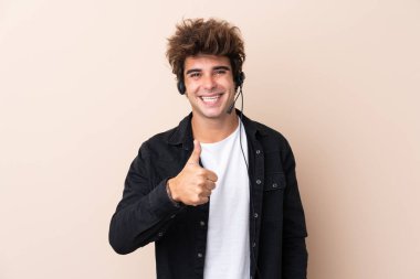 Tele pazarlamacı, izole edilmiş arka plan üzerinde çalışan bir kulaklıkla baş parmak işareti yapıyor.