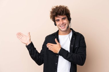 Telemarketer adam izole bir arka planda bir kulaklıkla çalışıyor. Davet etmek için ellerini yana uzatıyor.