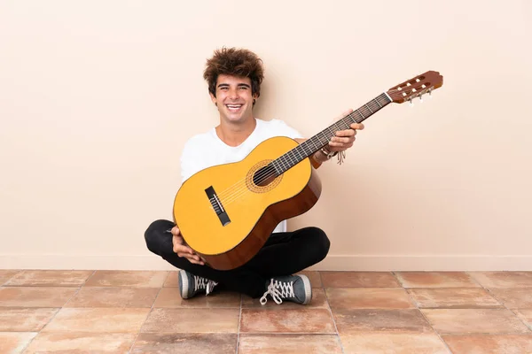 年轻的高加索人 带着一把吉他坐在地板上 满面春风 — 图库照片