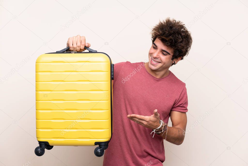 Young caucasian man over isolated background in vacation with travel suitcase