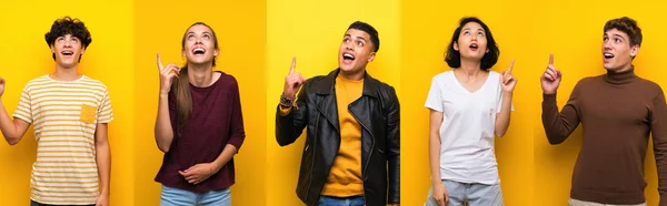 Set of people over isolated yellow background pointing up and surprised