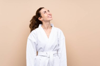 Karate yapan genç bir kadın gülümserken yukarı bakıyor.