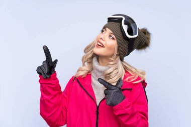 Snowboard gözlüklü genç kayakçı kız izole edilmiş mavi arka planda işaret parmağıyla işaret etmek harika bir fikir.