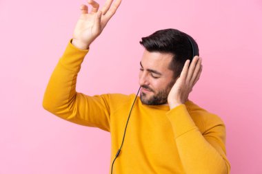 Sakallı yakışıklı genç adam soyutlanmış pembe müzik dinliyor.