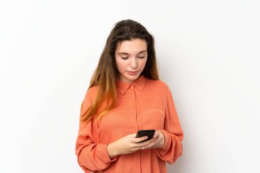 İzole edilmiş beyaz arka planda genç esmer kız cep telefonuyla bir mesaj gönderiyor.