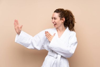 Tecrit edilmiş arka planda karate yapan genç bir kadın.