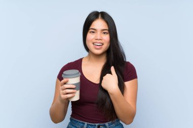 Genç Asyalı kız elinde sürpriz bir yüz ifadesiyle kahve tutuyor.