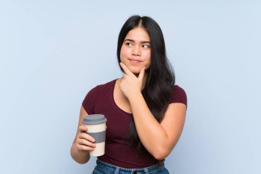 Genç Asyalı kız elinde kahve tutarken bir fikir üretiyor.