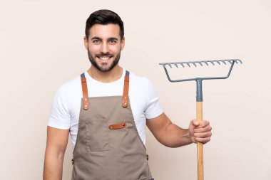 Bahçıvan arka planda bir tırmık tutuyor.