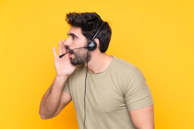 Tele pazarlamacı adam kulaklıkla çalışıyor izole edilmiş sarı arka planda ağzı açık bağırıyor.