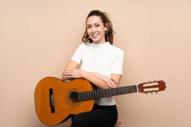 Arka planda gitar çalan genç bir kadın çok fazla gülümsüyor.