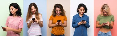 İzole edilmiş renkli arkaplan üzerindeki bir grup kadın cep telefonuyla bir mesaj gönderiyor