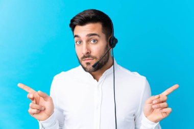 Tele pazarlamacı, mavi arka plan üzerinde çalışan bir kulaklıkla yan taraftakilerin şüphelerini işaret ediyor.