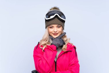 Kar kayağı gözlüklü genç kız izole edilmiş mavi arka planda gülüyor.