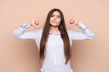 Izole arka plan üzerinde genç kadın başparmak aşağı gösteren