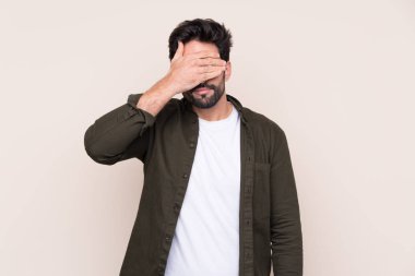 İzole edilmiş arka planda sakallı, genç ve yakışıklı bir adam. Gözlerini elleriyle kapatıyor. Bir şey görmek istemiyorum.