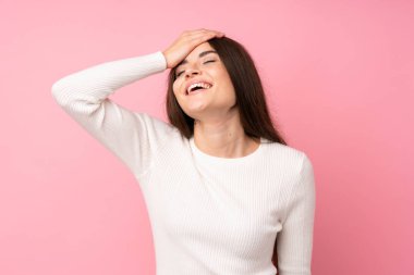 Genç bir kadın pembe arka planda gülüyor.