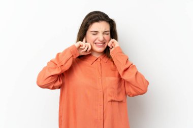 Genç esmer kız izole edilmiş beyaz arka planda hayal kırıklığına uğramış ve kulaklarını kapatmış.