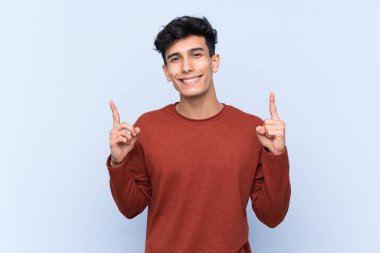 Arjantinli genç adam izole edilmiş mavi arka plan harika bir fikre işaret ediyor.