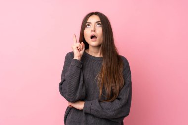 Soyutlanmış pembe arka planı olan genç bir kadın parmak kaldırmayı düşünüyor.