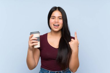 Genç Asyalı kız elinde kahve ile harika bir fikri işaret ediyor.