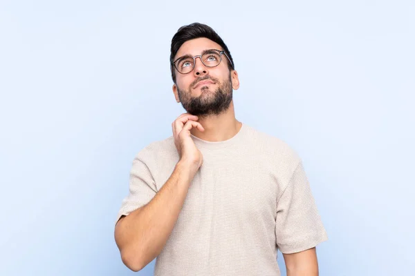 Joven Hombre Guapo Con Barba Sobre Fondo Azul Aislado Pensando — Foto de Stock